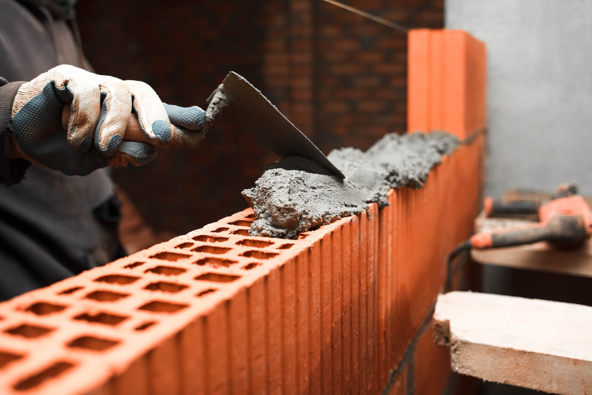 Bricklayer puts bricks to make a wall
